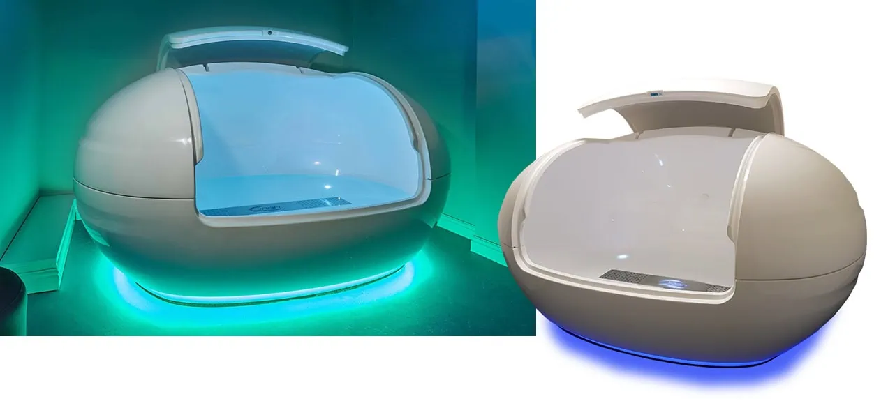 Two white fibreglass flotation pods that are egg shaped and open from the front, with LED coloured lighting underneath and water inside