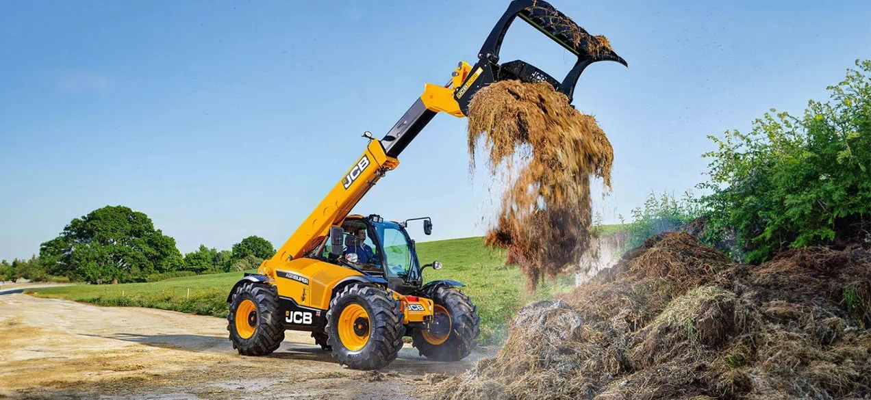  JCB excavator using its telescopic arm to move silage on a farm
