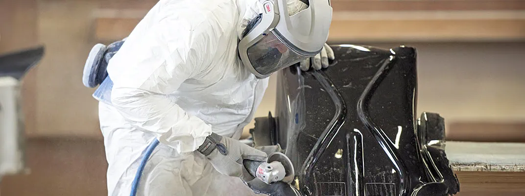 Operator in PPE trimming a GRP part in post-manufacturing phase