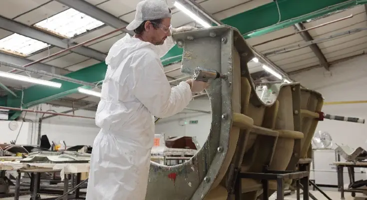 operator in white working on reinforcing a GRP mould